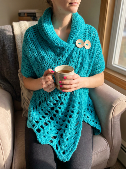 Rain Lily Crochet Poncho Pattern - seated cozy lifestyle shot with a warm mug of tea