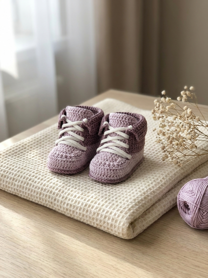 River Reed Crochet Baby Booties Pattern - pair of two-tone lilac crochet baby booties styled on an ivory waffle blanket
