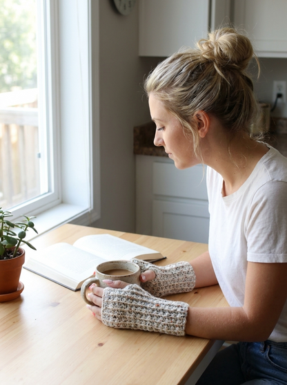 Chamomile Field Crochet Fingerless Gloves Pattern - wrist warmers worn at a kitchen table with a mug of coffee